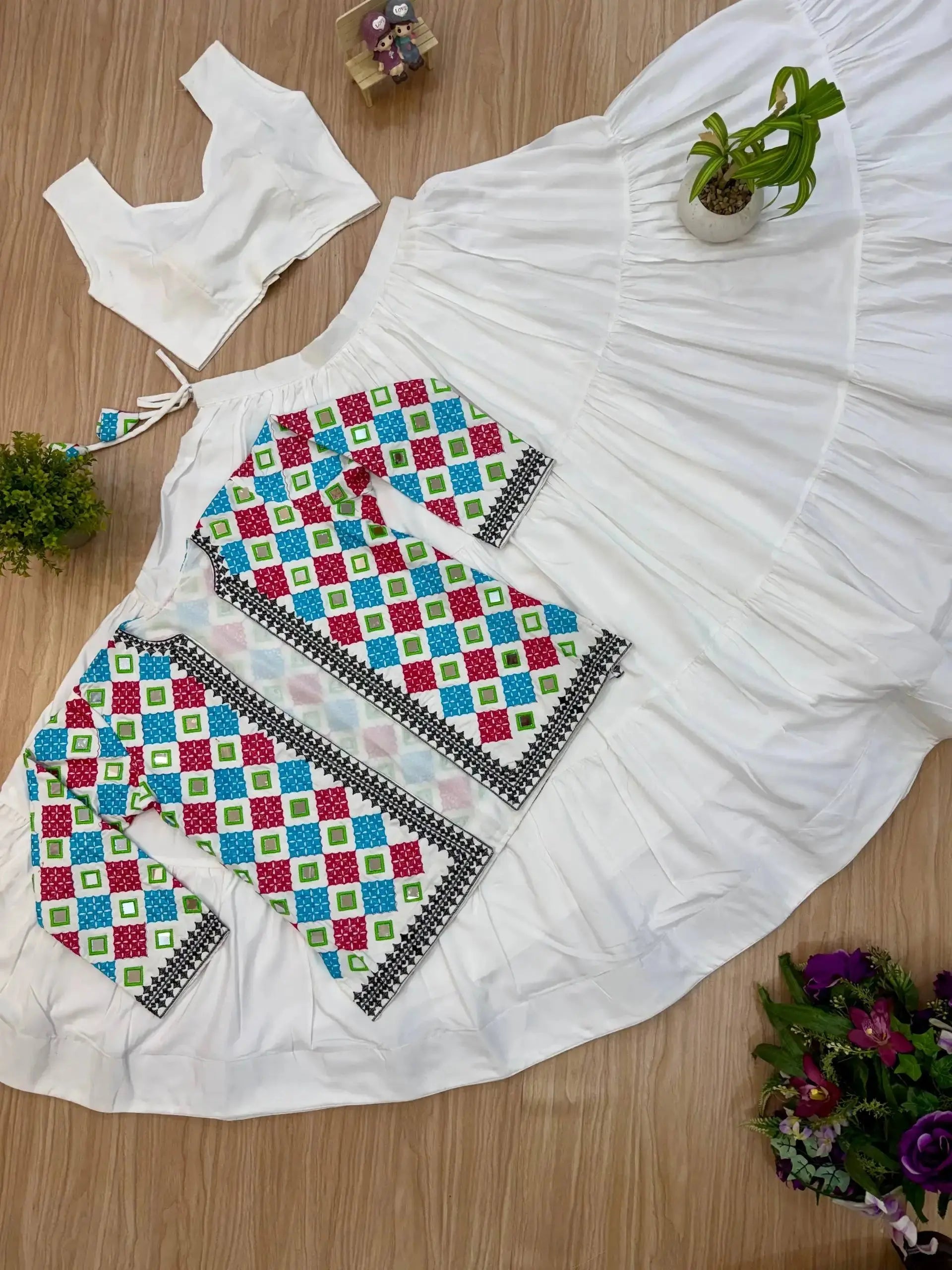 Close-up flat lay of bandhej koti and white tiered lehenga skirt, full 3-piece set view