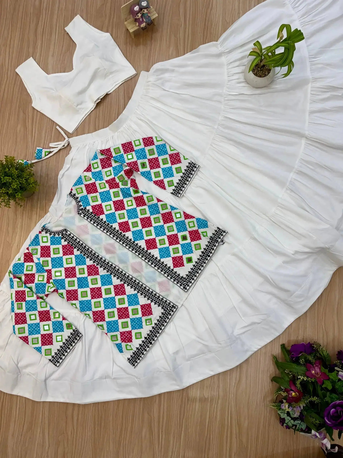 Close-up flat lay of bandhej koti and white tiered lehenga skirt, full 3-piece set view