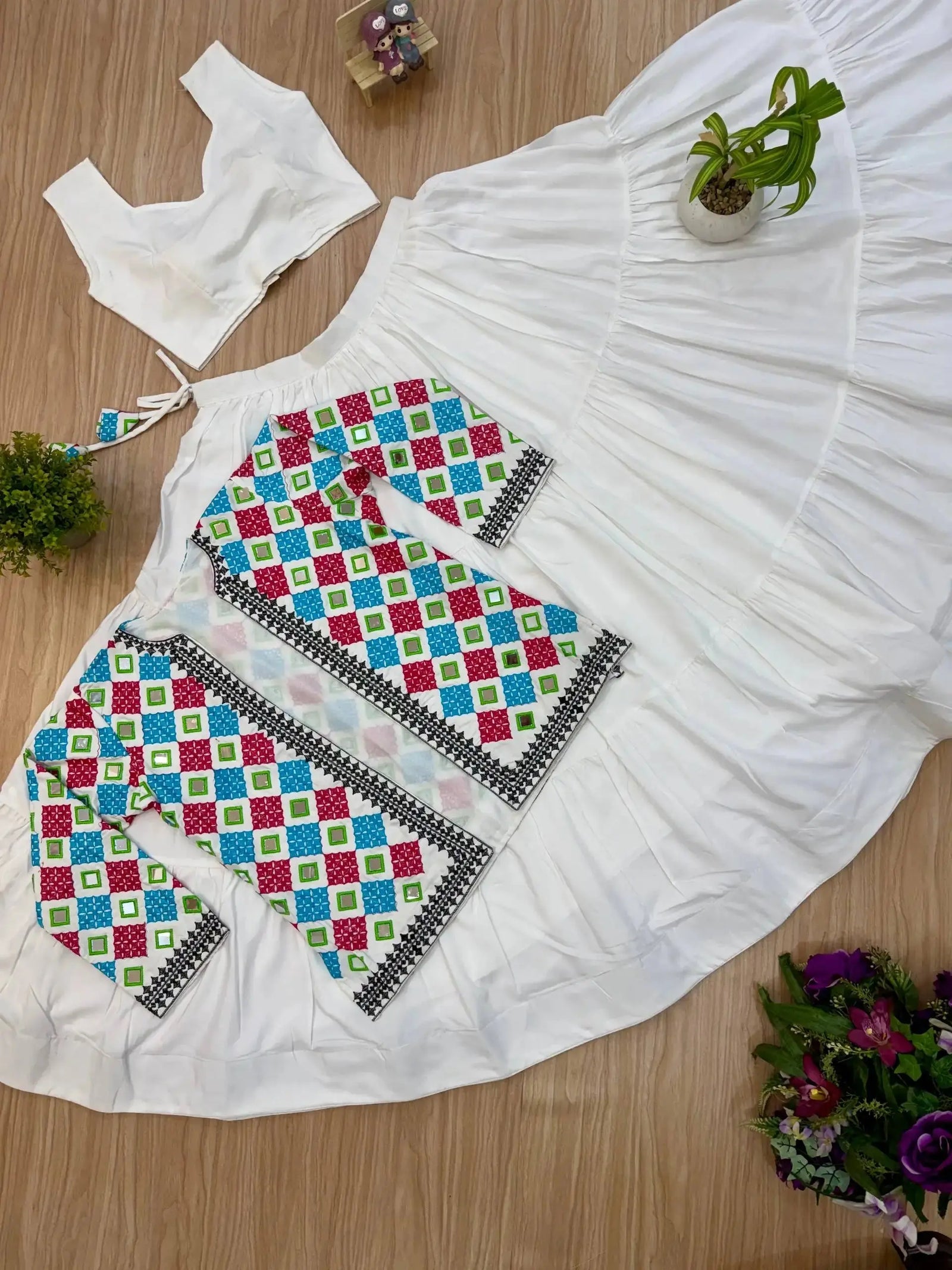 Close-up flat lay of bandhej koti and white tiered lehenga skirt, full 3-piece set view