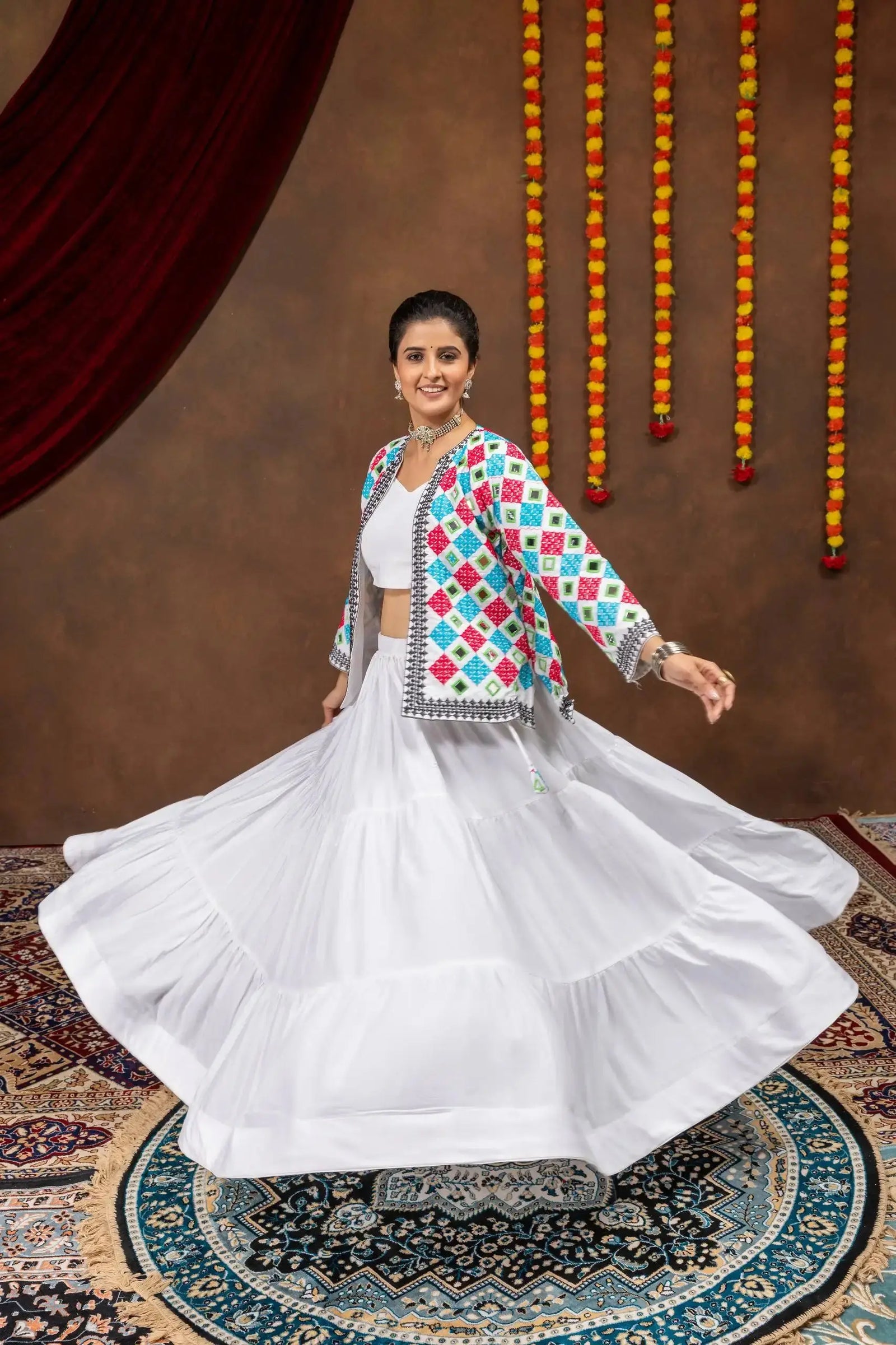 White tiered rayon lehenga twirling in motion with colorful bandhej mirror-work koti