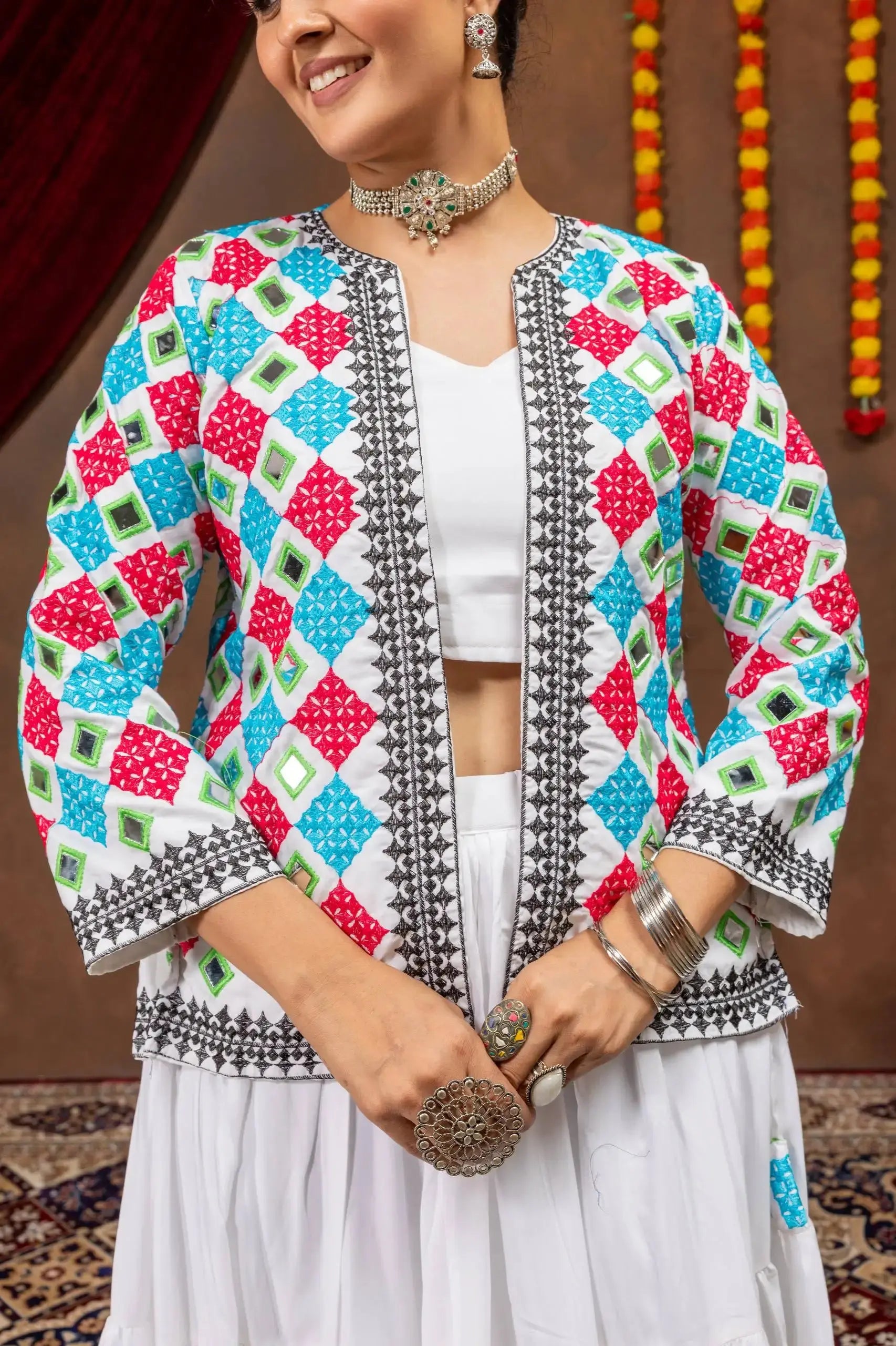 Close-up of open bandhej mirror-work jacket with pink, teal and green checkerboard print and black border