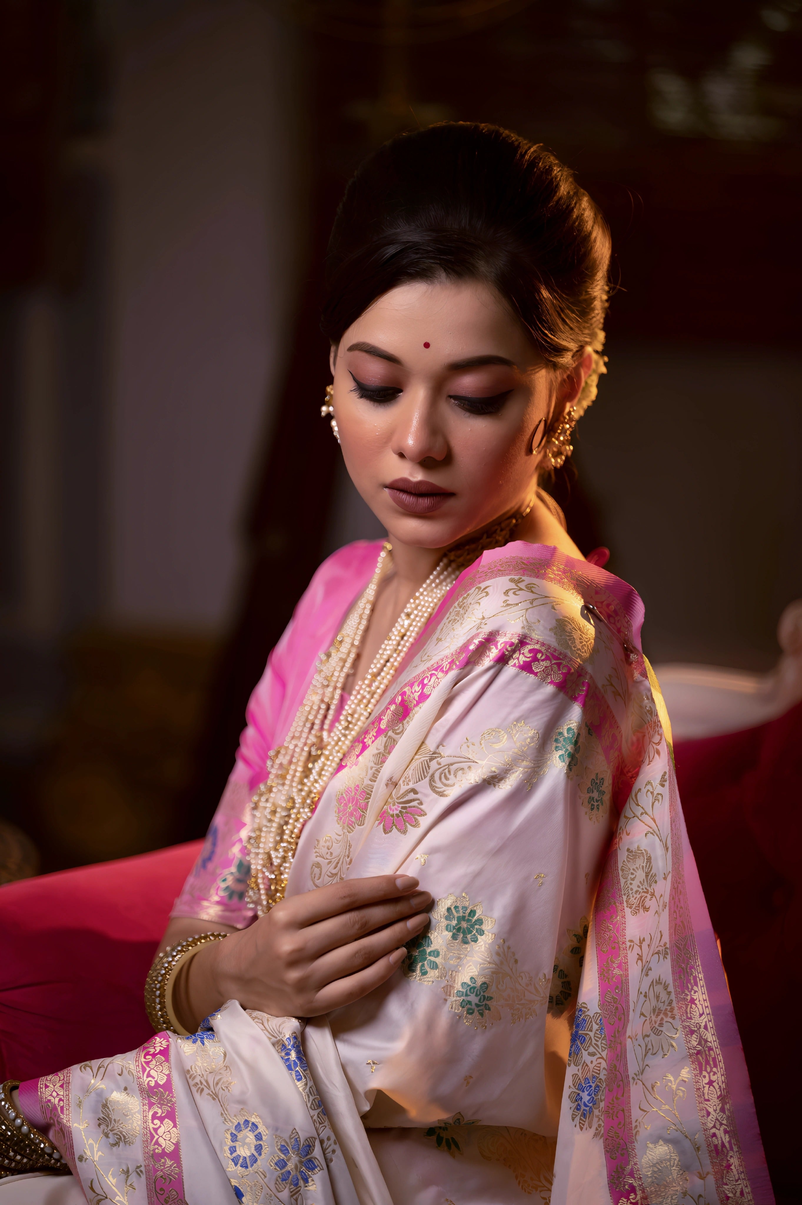 A woman models an opulent Off-White Soft Banarasi Silk Saree. The saree features multi-colored motifs and a wide Fuchsia Pink and gold Zari woven border and pallu with traditional patterns. She wears a contrasting pink long-sleeve blouse and heavy layered gold and pearl jewelry, posing in a luxurious, dramatically lit vintage setting.
Related
File name: modern-minimalist-architecture
Alt text: Sleek modern minimalist architecture with clean lines and large glass windows
