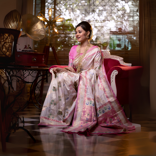 A woman models an opulent Off-White Soft Banarasi Silk Saree. The saree features multi-colored motifs and a wide Fuchsia Pink and gold Zari woven border and pallu with traditional patterns. She wears a contrasting pink long-sleeve blouse and heavy layered gold and pearl jewelry, posing in a luxurious, dramatically lit vintage setting.
Related
File name: modern-minimalist-architecture
Alt text: Sleek modern minimalist architecture with clean lines and large glass windows.