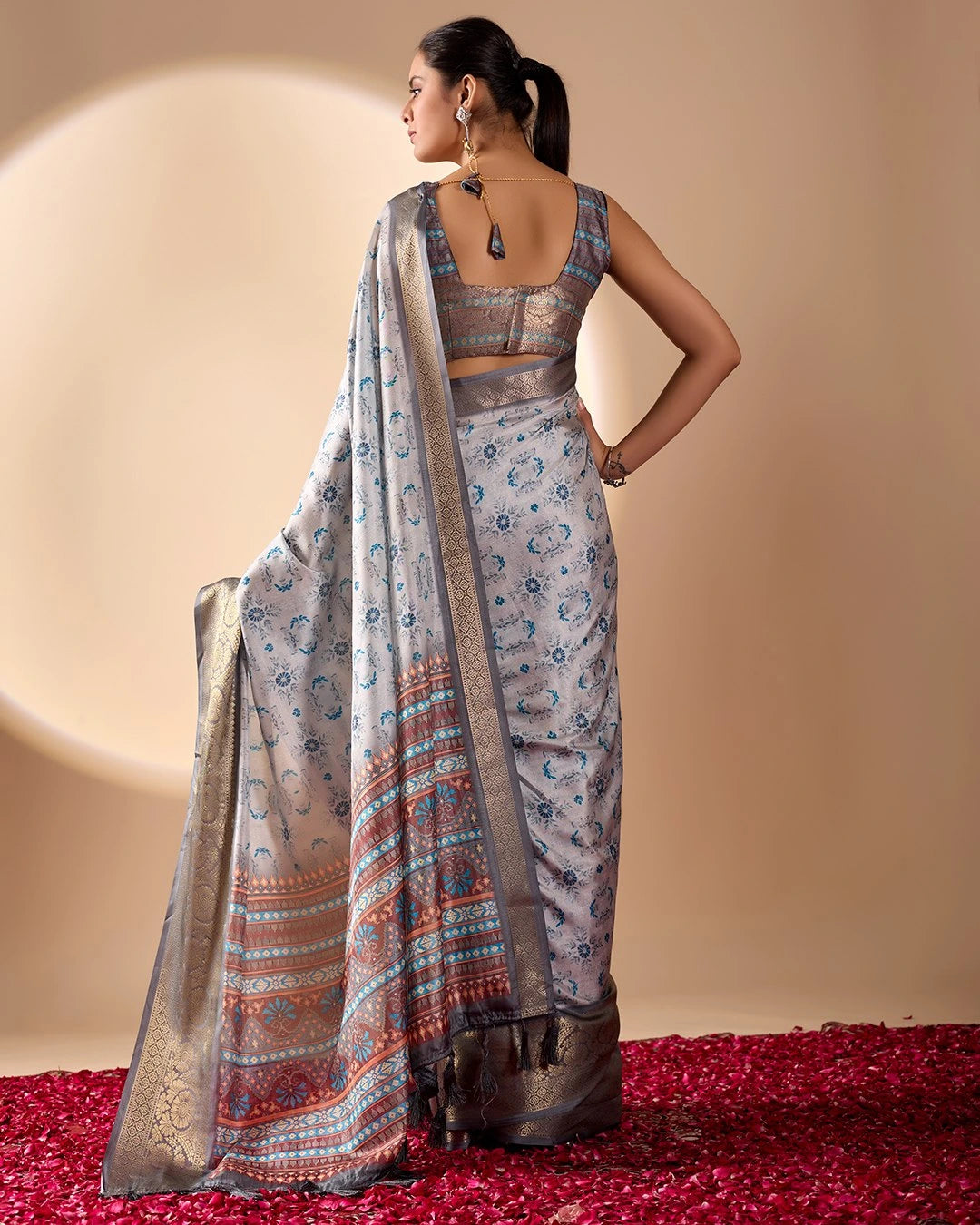 Woman wearing a traditional saree with a patterned blouse against a neutral background