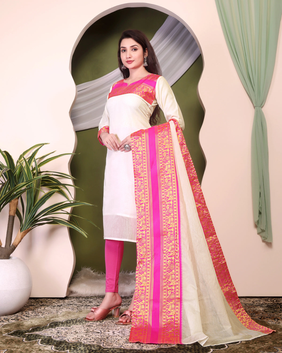 Woman wearing a traditional outfit with white and pink design, standing indoors.