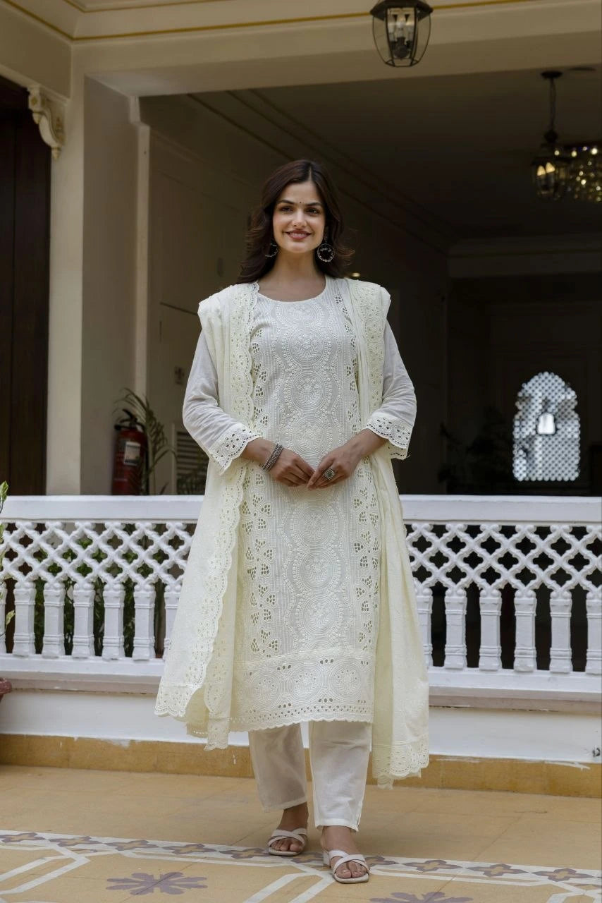 Woman in a white traditional outfit standing in a decorative indoor setting.