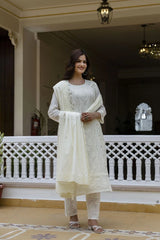 Woman in a white traditional outfit standing on a balcony