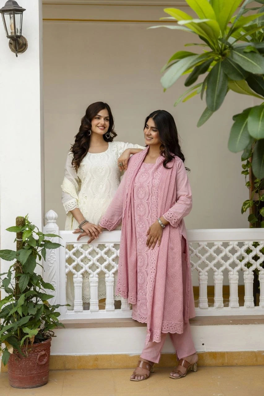 Two women standing on a porch with plants and a white railing.