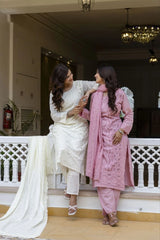 Two women in traditional attire sitting on a staircase indoors.
