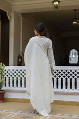Woman in a white traditional outfit standing on a balcony
