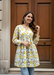 Woman wearing a floral dress standing in front of a wooden door.