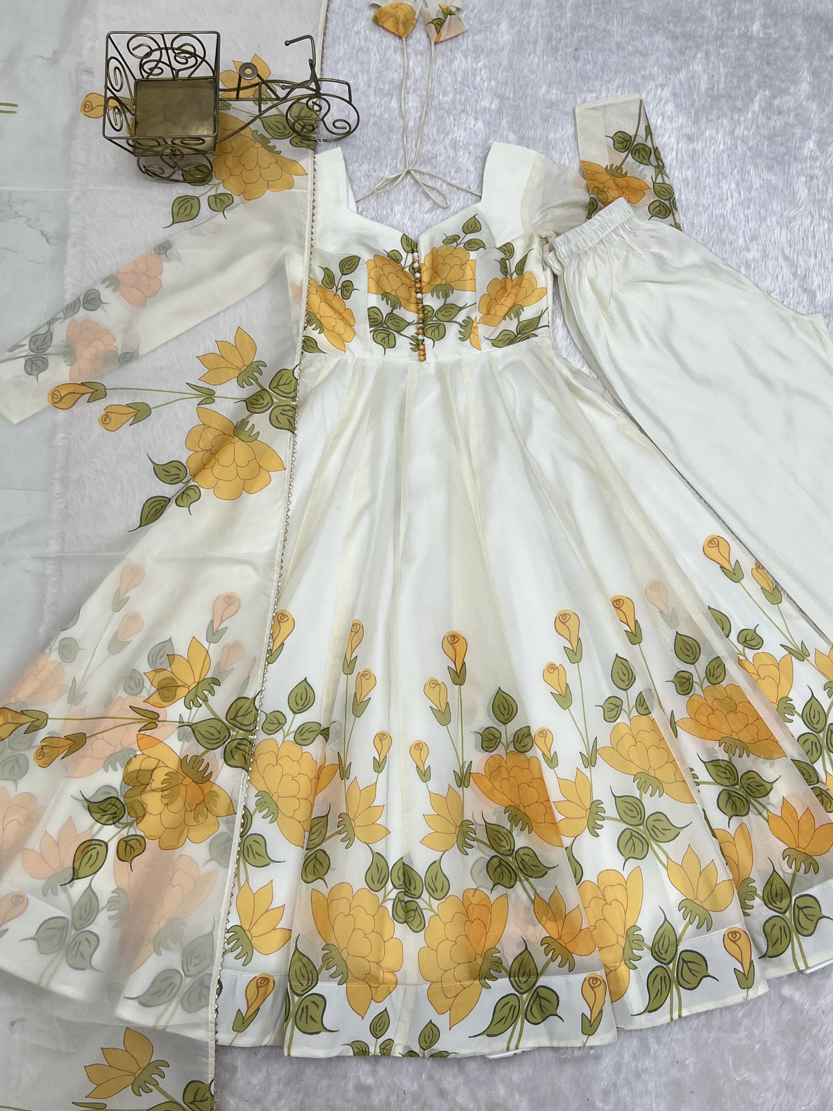 White dress with yellow floral pattern on a textured surface