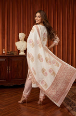 Woman in a traditional outfit with a patterned dupatta in a room with wooden furniture and a bust.