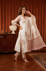 Woman in a traditional outfit with floral patterns in a room with wooden furniture and decor.