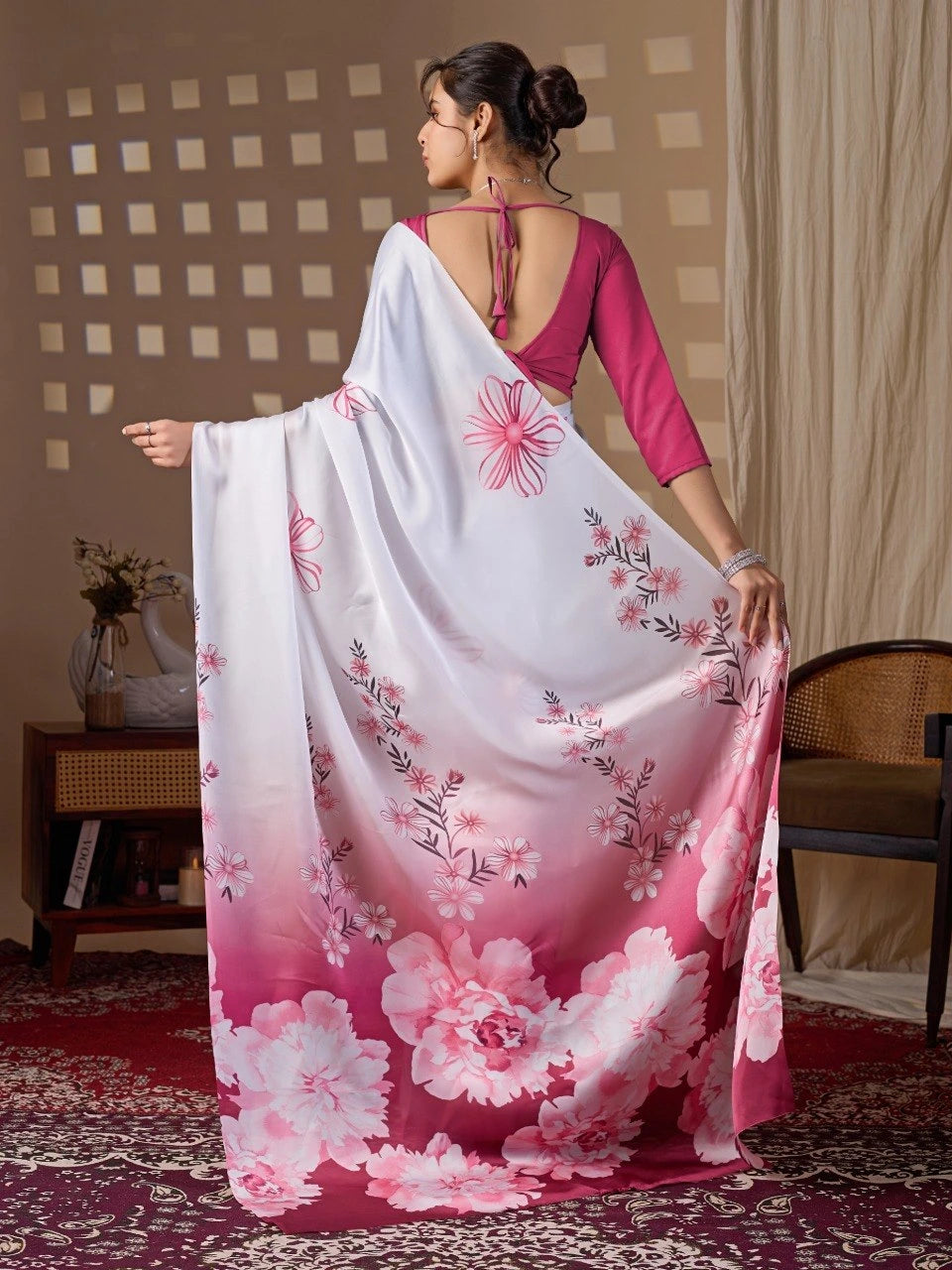 Woman wearing a floral saree with a pink blouse in a room setting.