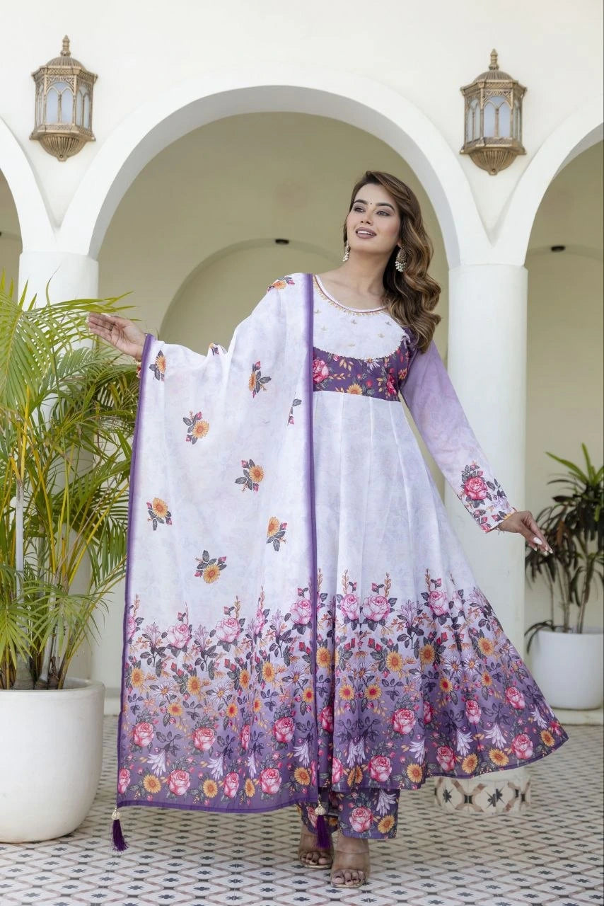 Graceful ethnic wear featuring a white and lavender floral Anarkali, printed pants, and a lightweight dupatta for festive occasions.