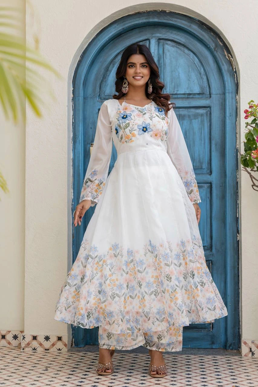 Woman wearing a white floral dress standing in front of a blue door.