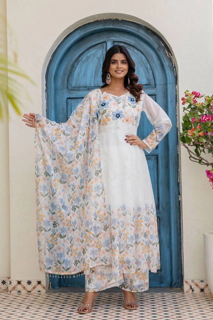 Woman in a white floral dress standing in front of a blue door with decorative elements.