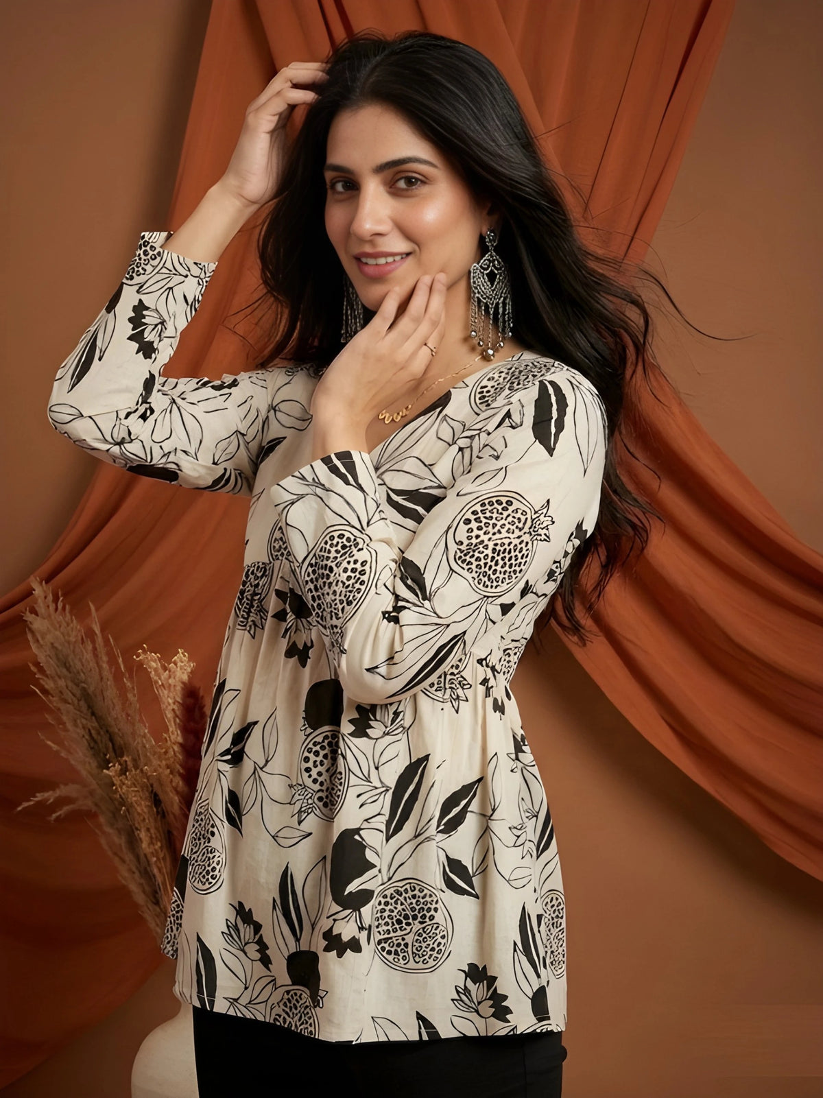 Woman wearing a floral patterned top against an orange curtain background