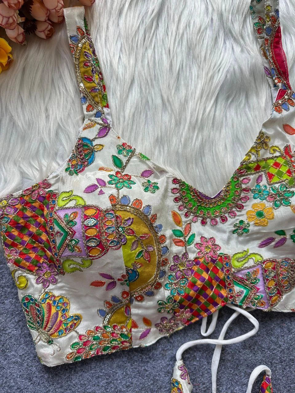 Colorful embroidered blouse with floral patterns on a white fur surface
