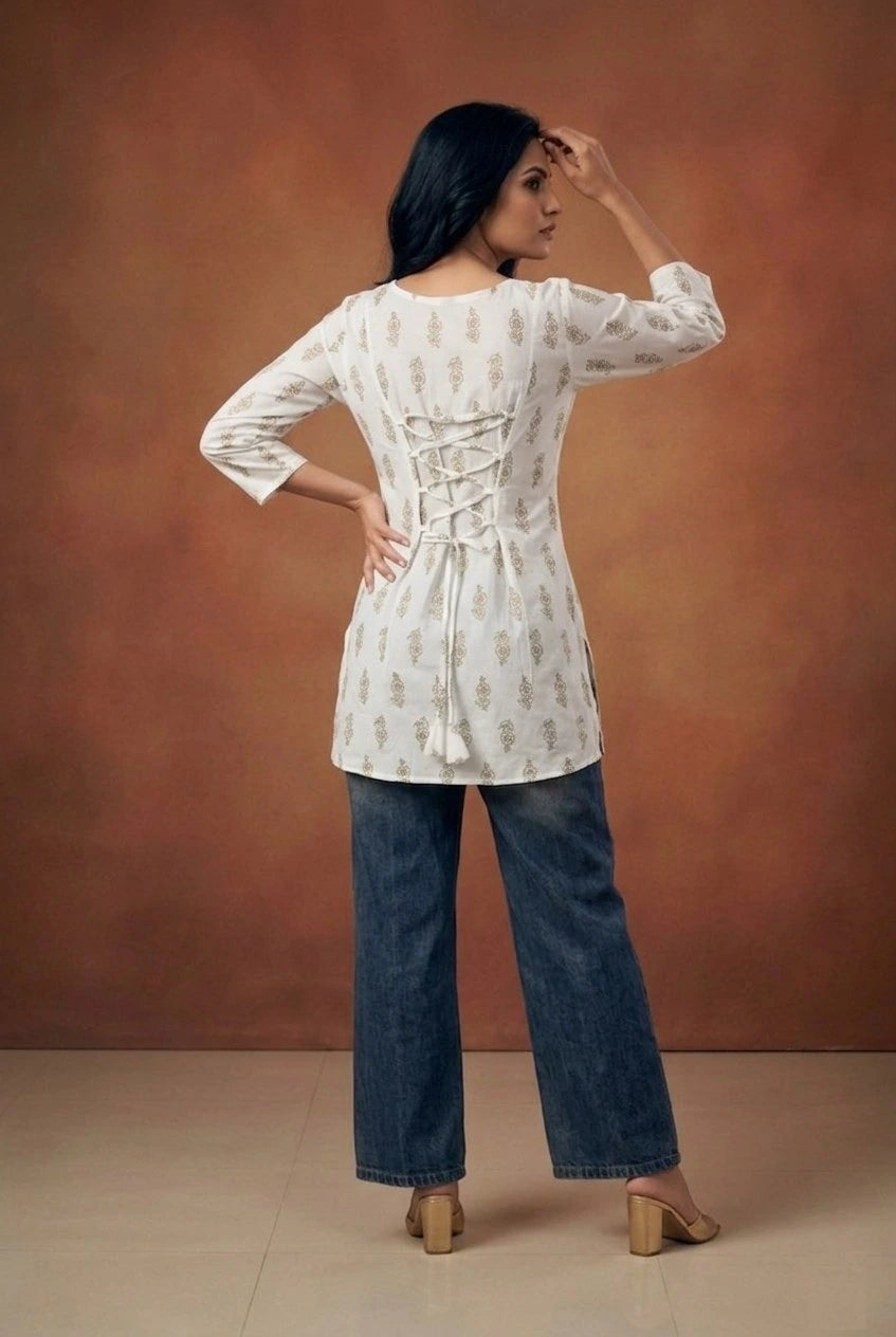 Woman wearing a white blouse with lace details and blue jeans against a brown background