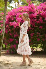 Woman in a floral dress standing in front of pink flowers