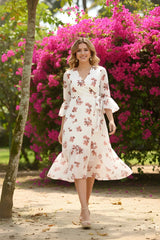 Woman in a floral dress standing in front of pink flowers