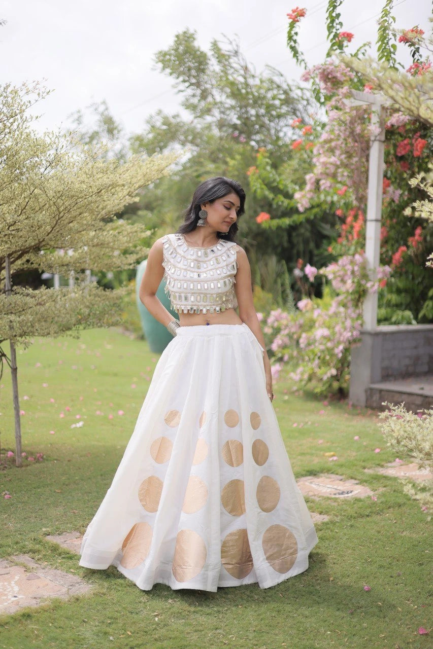 Gorgeous white lehenga with shimmering mirror embellishments and golden accents offers timeless festive charm and sophistication.