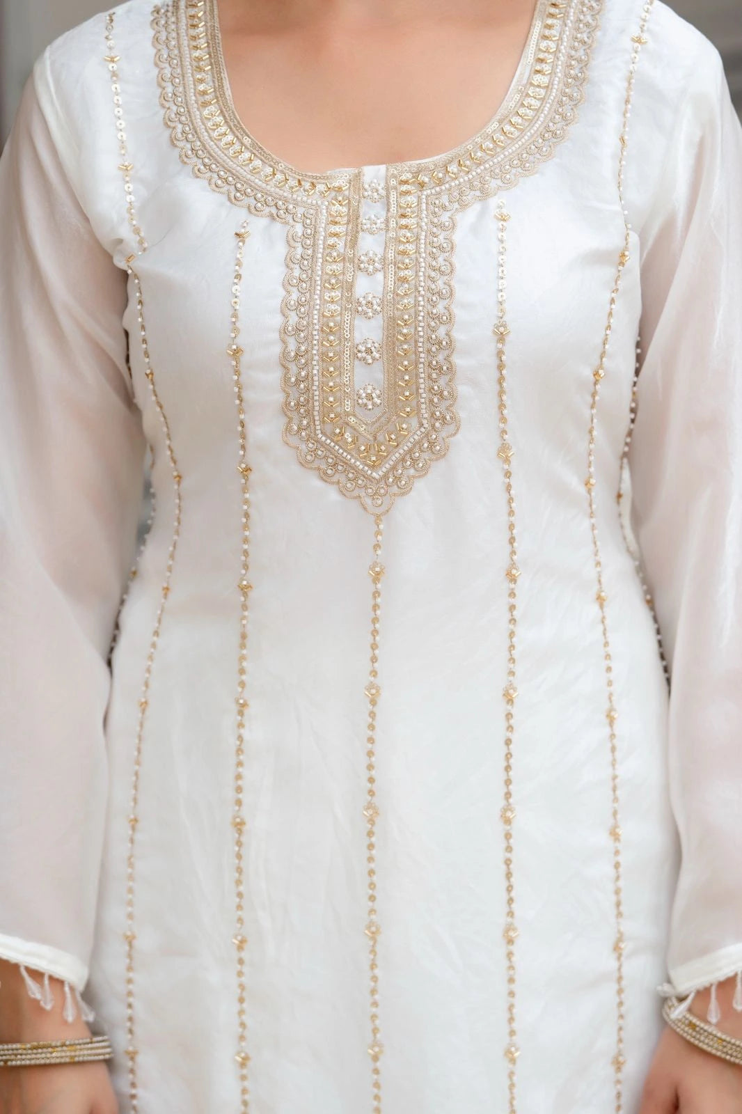 White dress with gold embroidery on a plain background