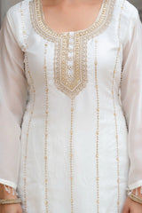 White dress with gold embroidery on a plain background