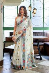 Woman wearing a floral saree in an indoor setting with tables and chairs.