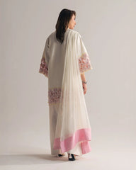 Woman wearing a cream and pink traditional outfit with floral embroidery on a plain background