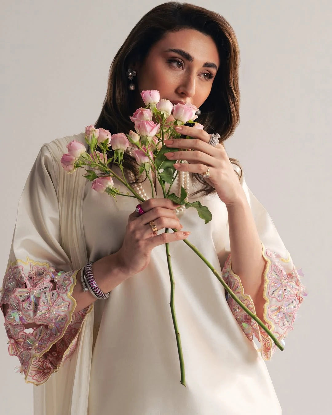 Woman holding a bouquet of pink flowers against a plain background