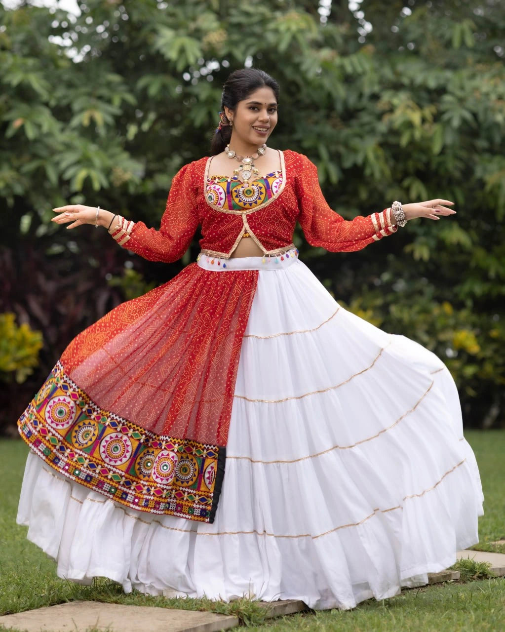 Woman in traditional red and white outfit with colorful patterns outdoors.