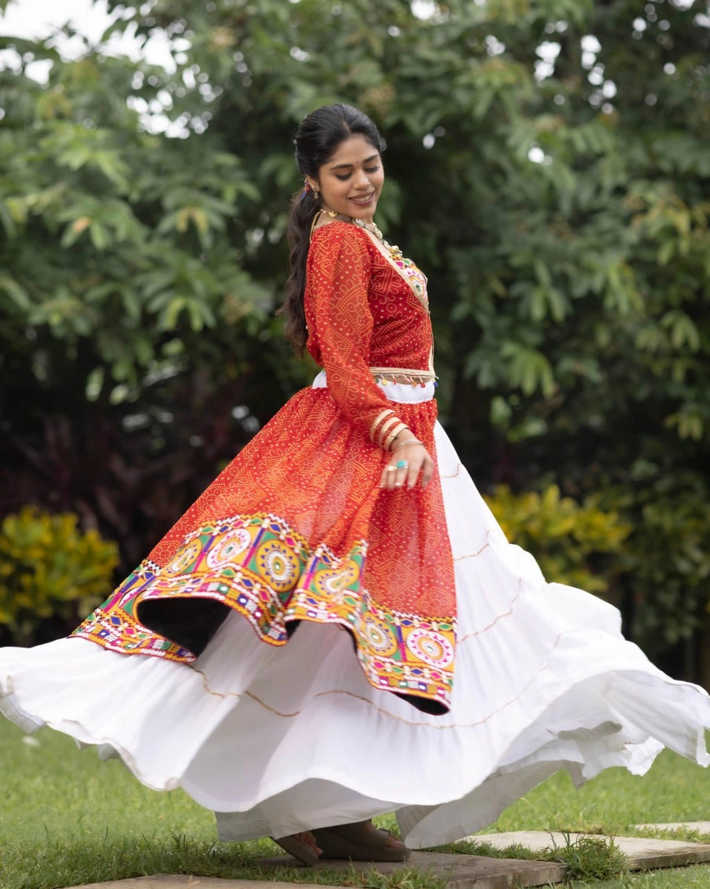 Woman in a traditional outfit with a red and white dress in a garden setting