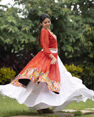 Woman in a traditional outfit with a red and white dress in a garden setting