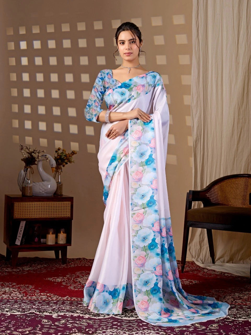 Woman wearing a white saree with floral patterns in a room setting