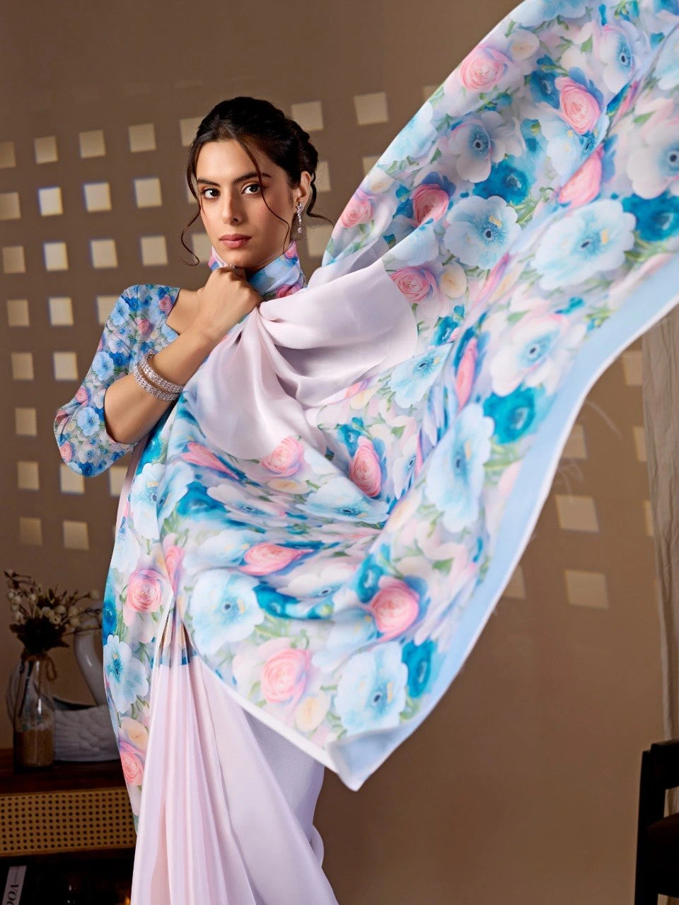 Woman holding a floral-patterned saree with a neutral background