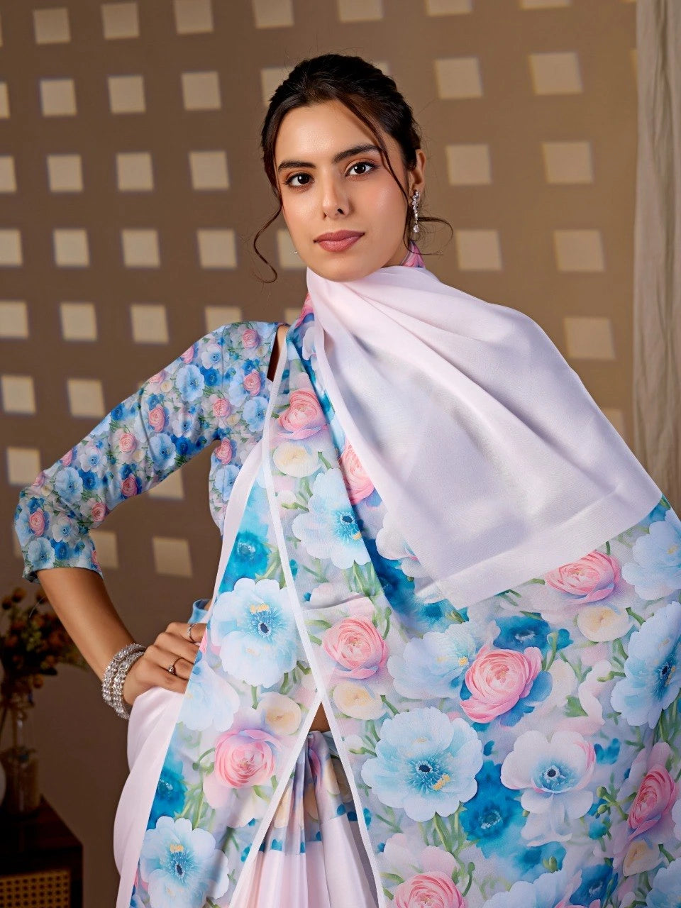 Woman wearing a floral saree with a white blouse against a checkered wall.