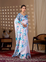 Woman wearing a floral saree in a room with a checkered wall and a chair.