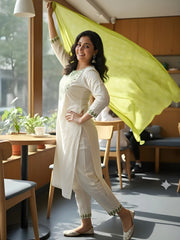 Woman in a white traditional outfit with a yellow scarf in a modern cafe setting