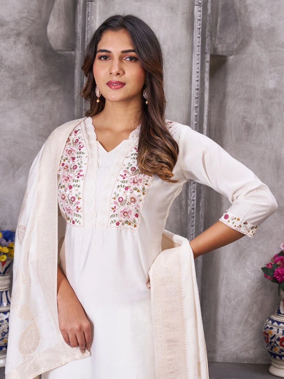 Woman wearing a white outfit with floral embroidery in a decorative setting