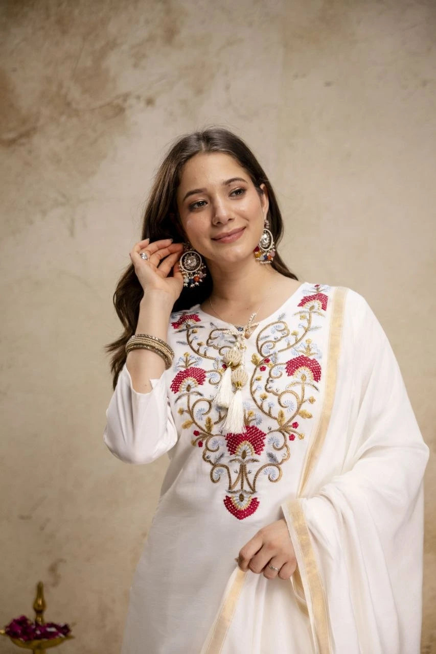Woman wearing a white embroidered outfit with a beige background