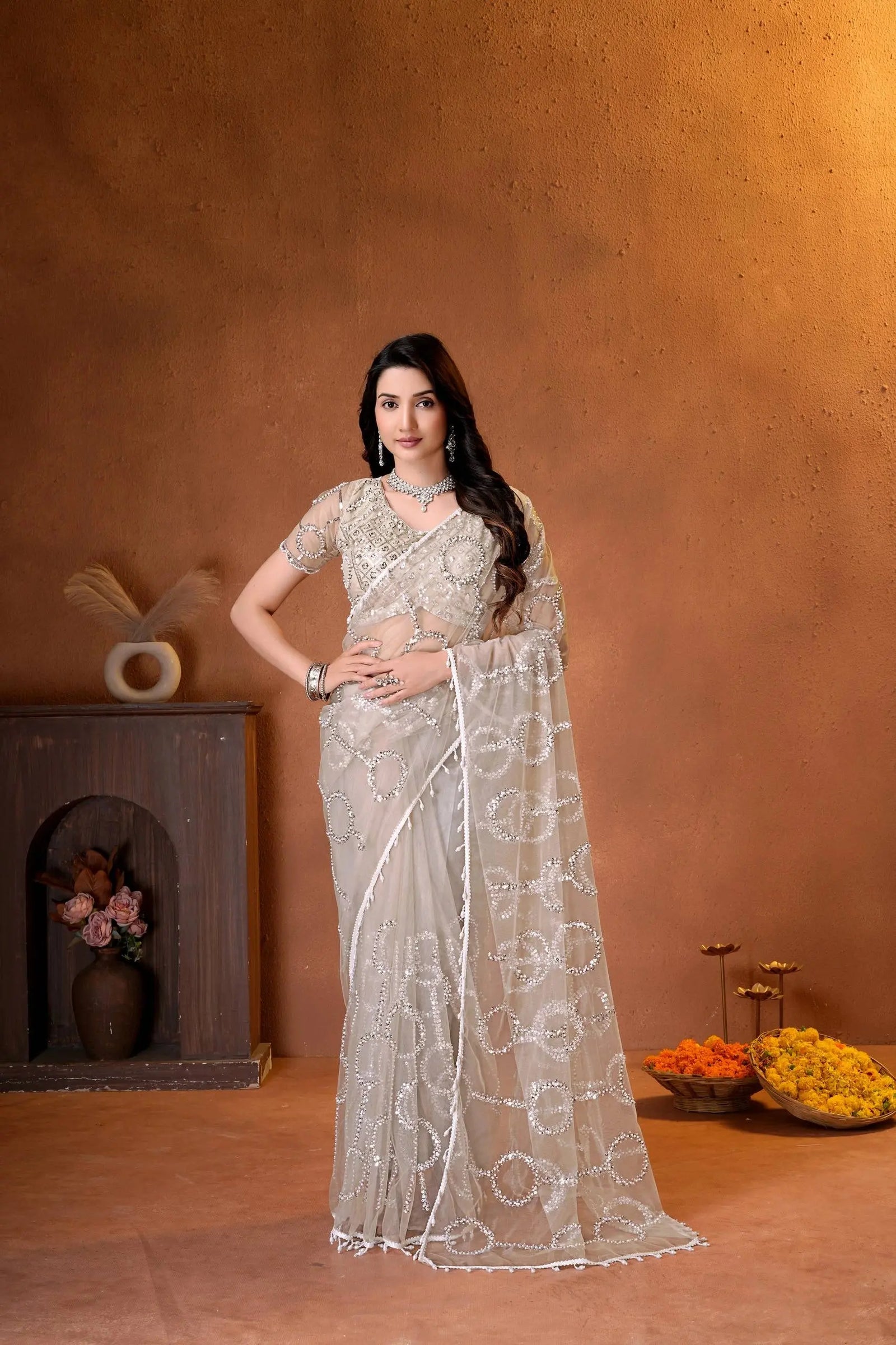 Elegant champagne beige designer saree featuring shimmering sequins embroidery and intricate handcrafted detailing for a graceful festive look.