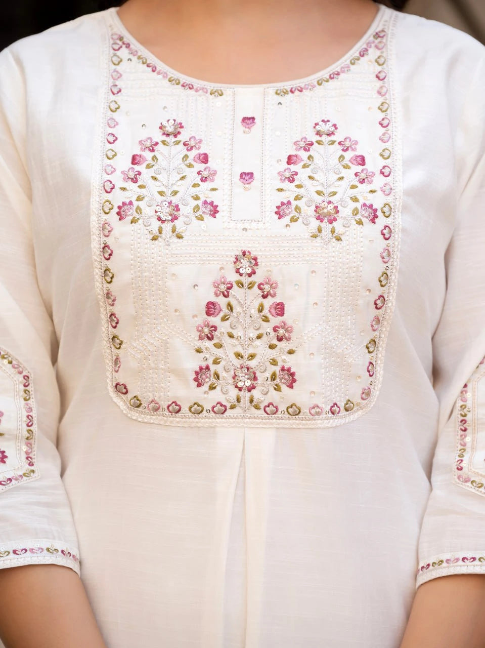Close-up of a white kurta with floral embroidery on a plain background