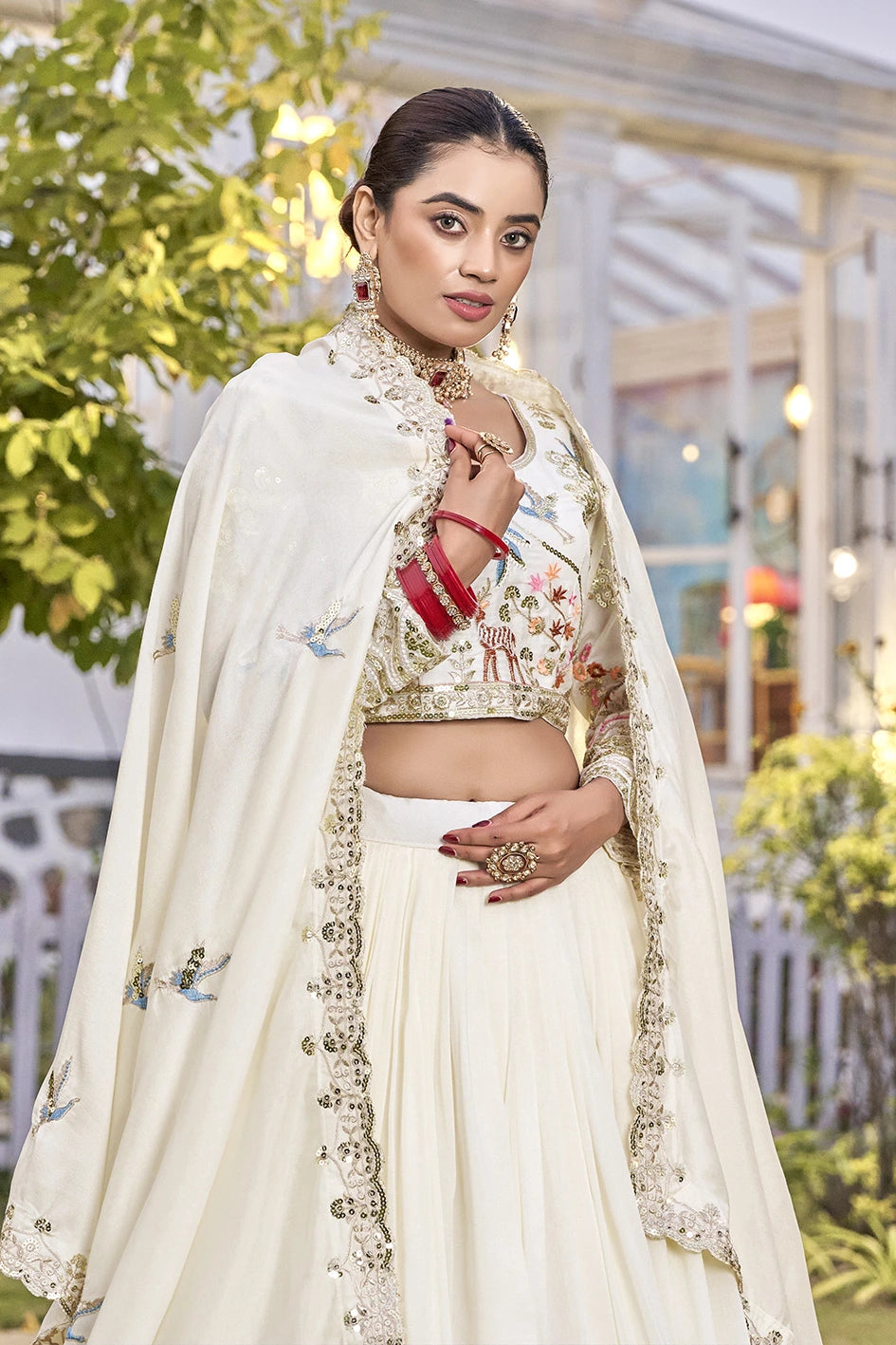 Woman in traditional outfit with floral blouse and white dupatta outdoors