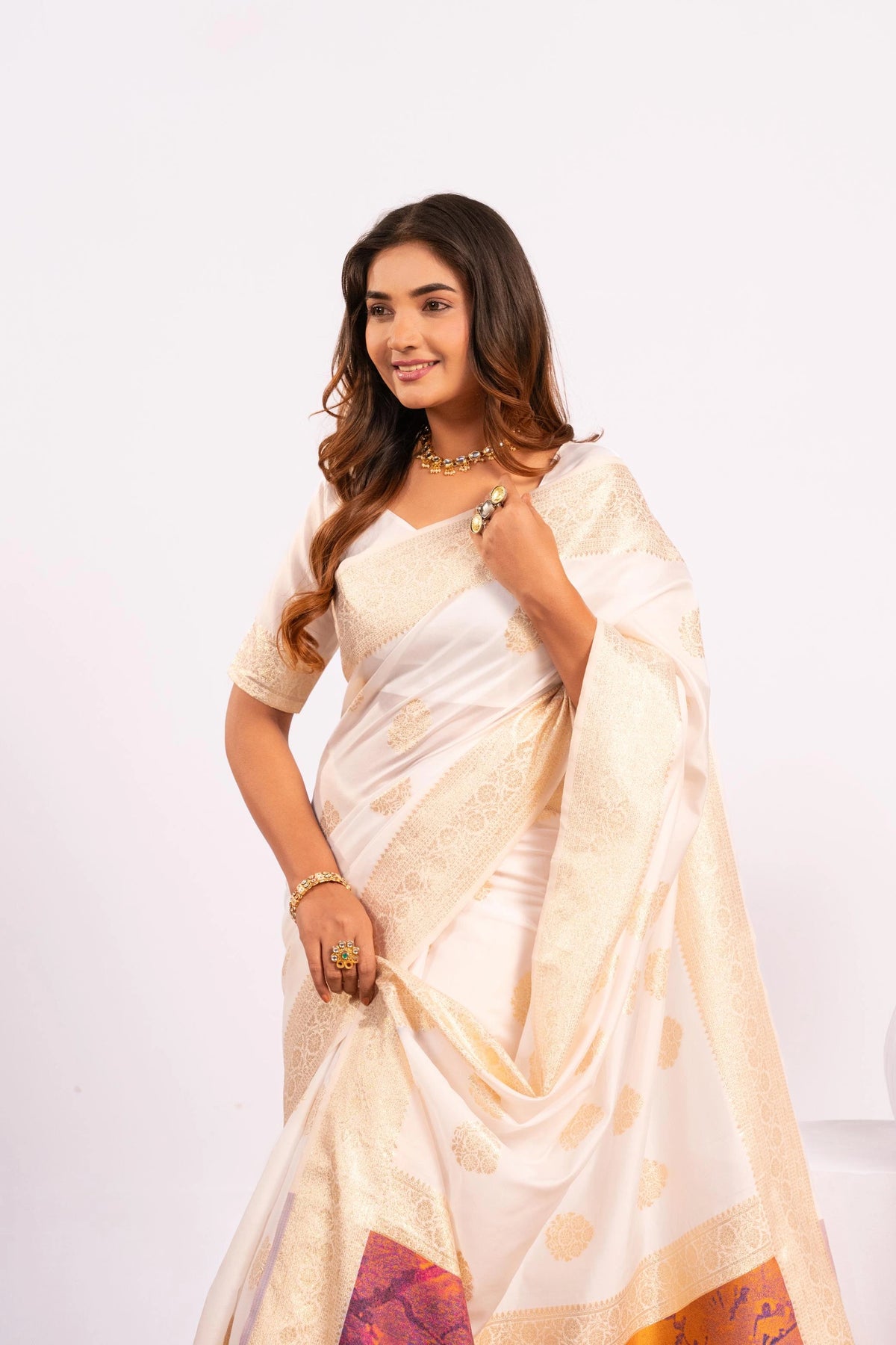 Woman wearing a white saree with a colorful border on a white background