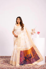 Woman wearing a white saree with a colorful design, standing against a plain background.