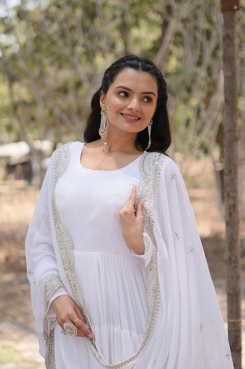 Woman in a white traditional outfit with a light shawl outdoors.