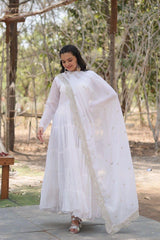 Woman in a white traditional outfit with a long scarf in an outdoor setting